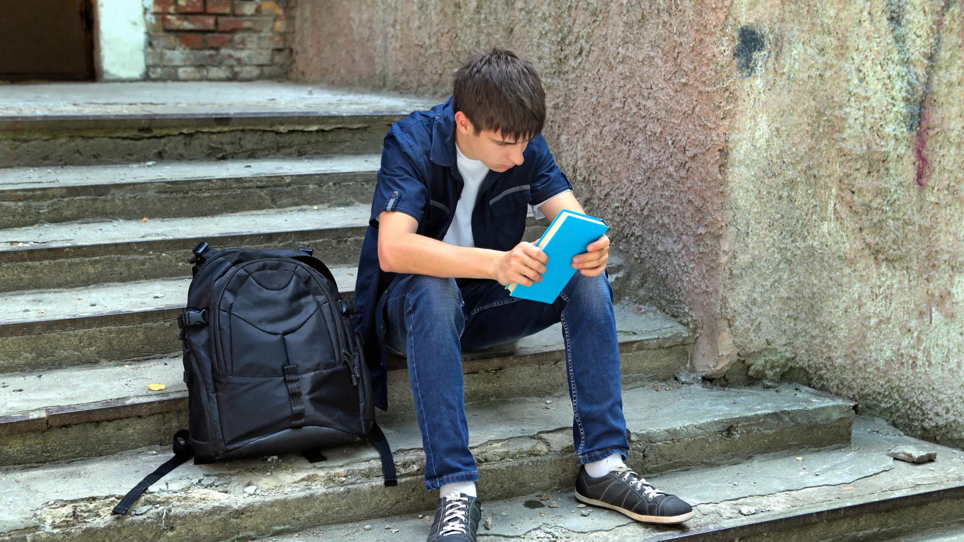 Alumno sentado en unas escaleras