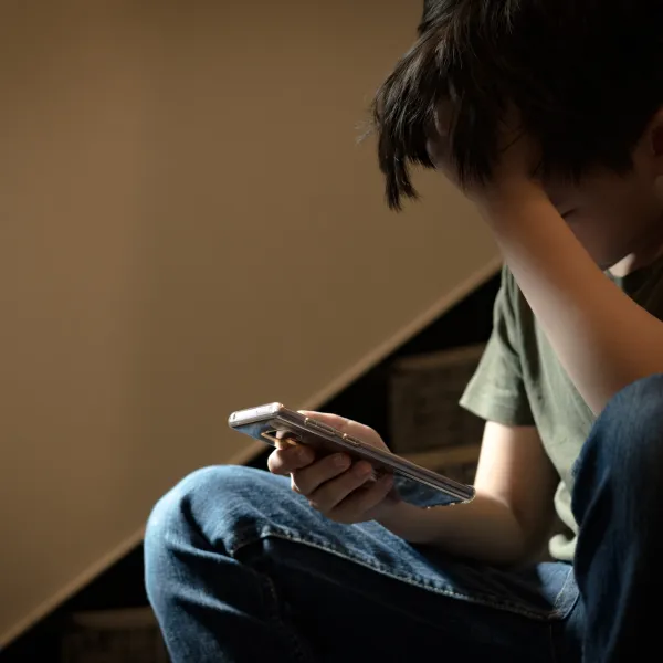 Niño triste con móvil en la mano